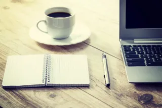 A notebook beside a laptop at a work table