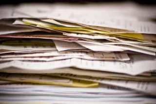 Close-up of an uneven stack of printed receipts, invoices and other paper records.