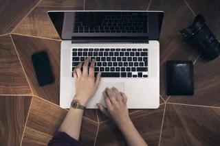 A person using a laptop at a work desk