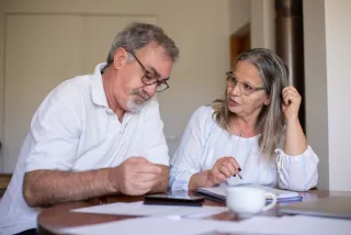 Two adults reviewing paperwork together at a table at home.